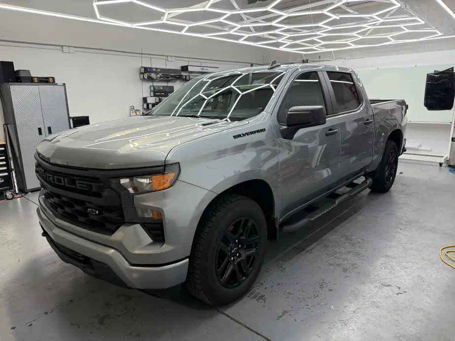 The DDM Services bay: a grey Silverado under the hexagon ceiling, Union film on the shelf behind